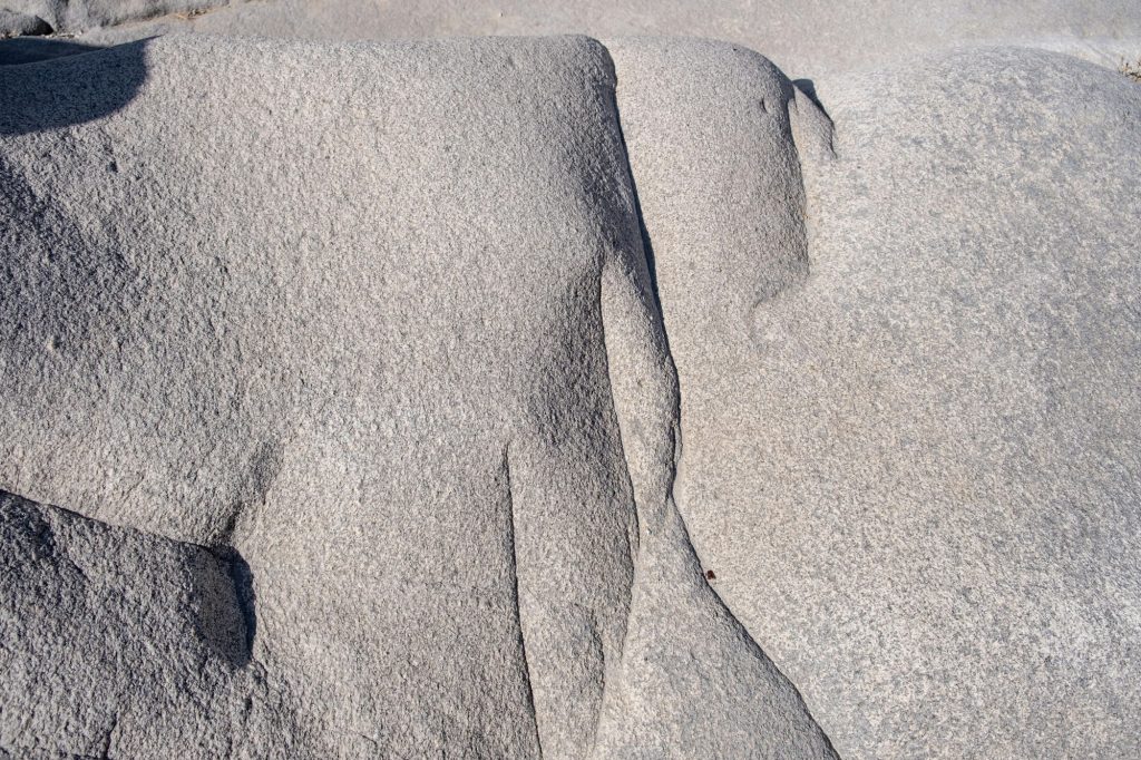 Granite grey rock shaped by the sea salt and wind background texture. Smooth mineral surface